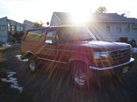 1995 Ford Bronco - Maroon 1995 Ford Bronco SUV parked outside on a sunny day.