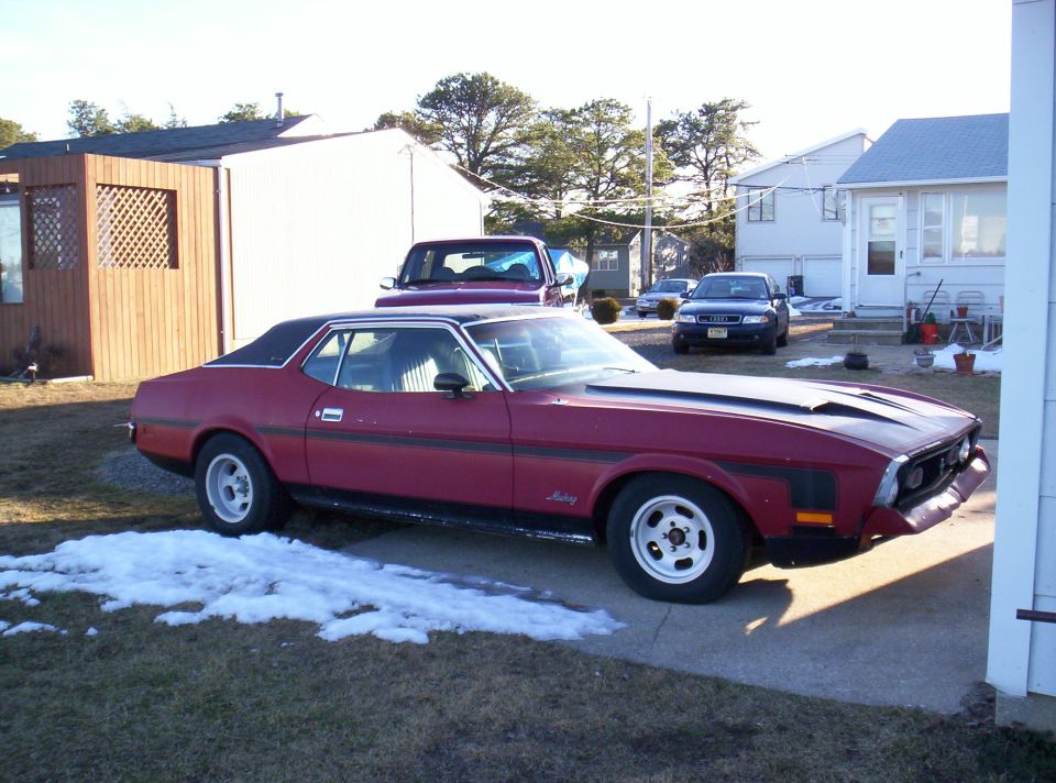 1971 Ford Mustang coupe with a black vinyl roof and hood scoops parked in a driveway