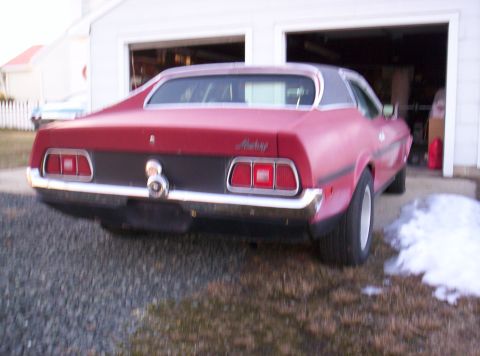 1971 Ford Mustang - Rear view of a red 1971 Ford Mustang coupe parked in front of a garage.