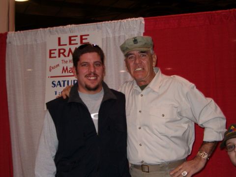 1993 Ford Bronco - Two men pose for a photograph in front of a red backdrop with a partial sign visible.