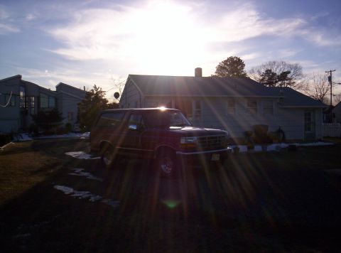 1995 Ford Bronco - A Ford Bronco is parked in a residential driveway during a sunny day with lens flares.