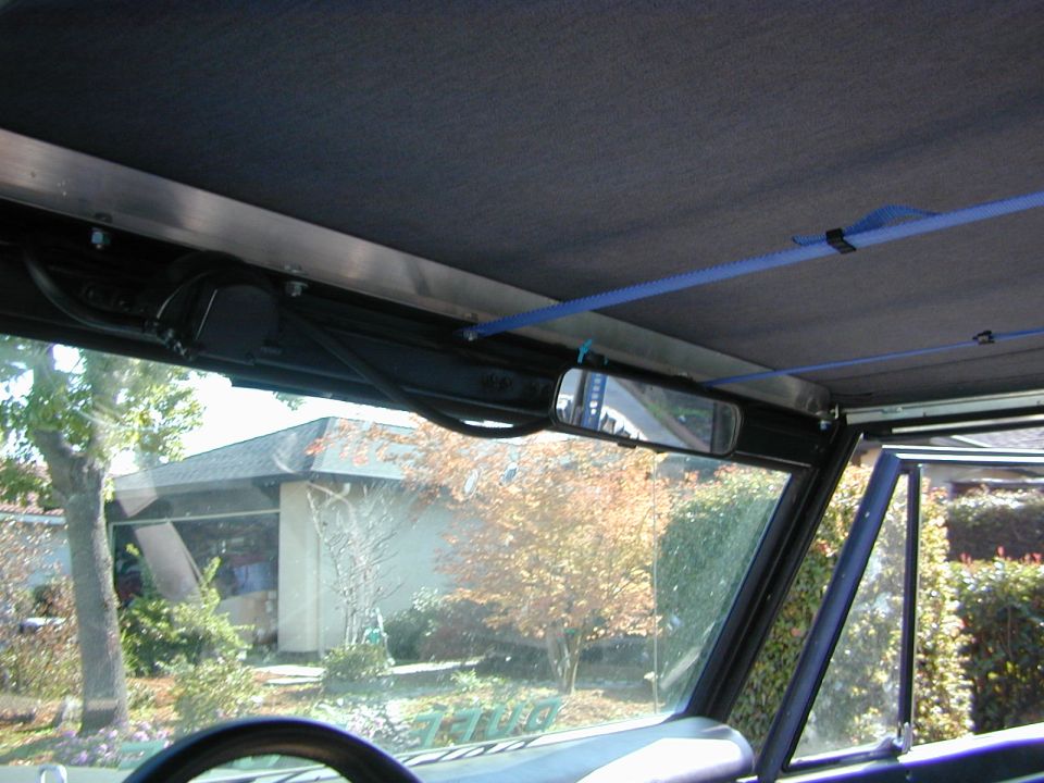 Interior view of Bronco windshield header with rearview mirror, gray soft top, and blue strap