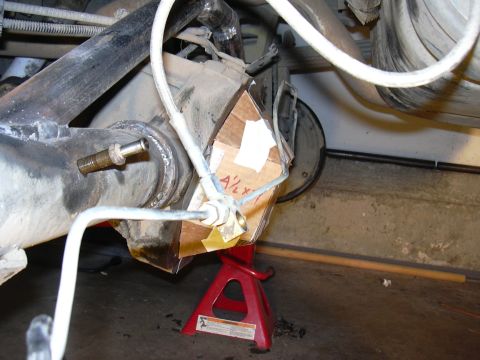 1991 Ford Bronco - Underbody shot of a rear axle housing supported on a red jack stand, with fresh weld beads around the tube-to-housing joint and a cardboard…