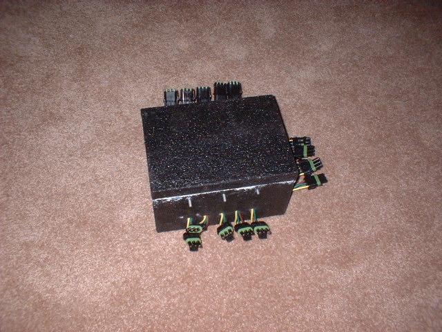 Black automotive electrical box with multiple connectors on a carpeted surface