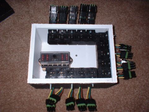 1986 Ford F-250 - A custom-built fuse box with numerous relays and connectors is shown, with wiring extending from the bottom and sides.