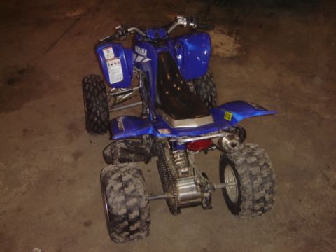 1992 Ford Bronco - Rear view of a blue Yamaha ATV with knobby tires and a silver exhaust pipe.
