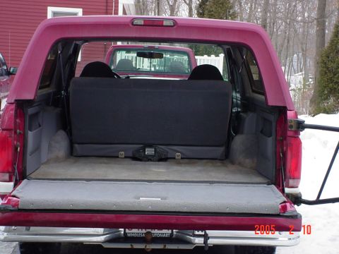 1994 Ford Bronco - The rear cargo area of a maroon Ford Bronco is shown, with another red vehicle visible in the background.