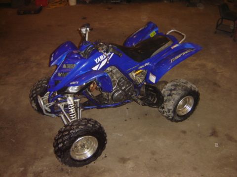 1992 Ford Bronco - A blue Yamaha Raptor ATV is parked indoors on a concrete floor.
