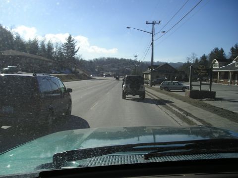 1996 Ford Bronco - A view from a vehicle driving on a road with other cars and buildings visible.