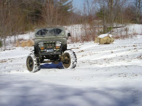 1996 Ford Bronco - Olive green Jeep Wrangler TJ navigates a snowy, off-road terrain.
