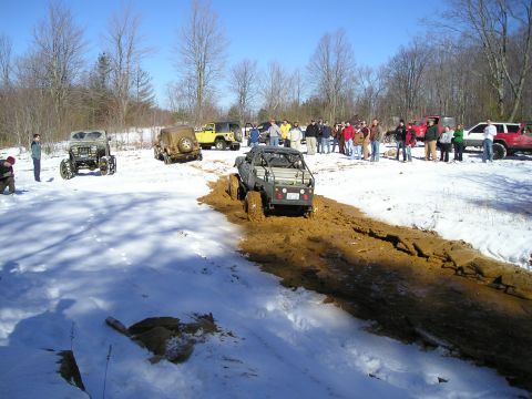 1996 Ford Bronco - Several off-road vehicles are seen participating in an event in a snowy and muddy environment.