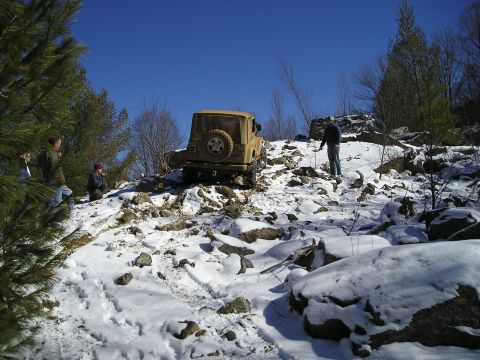 1996 Ford Bronco - Jeep Wrangler navigating a challenging snowy and rocky terrain.
