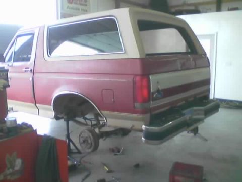 1989 Ford Bronco - This 1989 Ford Bronco is shown in a garage with its rear bumper and wheel removed, indicating it is undergoing maintenance or repair.