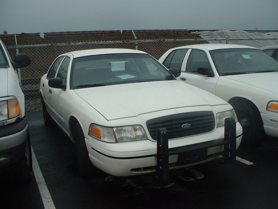 White sedan with a black push bar and grille, parked next to another white sedan