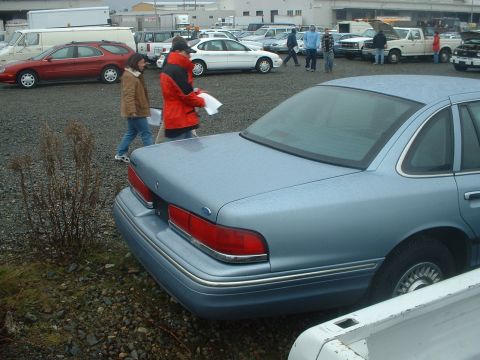 1999 Ford Crown Victoria - Rear view of a light blue sedan parked in an outdoor lot with other vehicles.