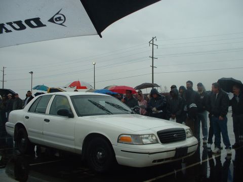 1999 Ford Crown Victoria - White Ford Crown Victoria sedan at an outdoor event on a rainy day with a crowd watching.