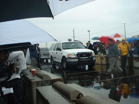 1999 Ford Crown Victoria - A white 1999 Ford Expedition is shown from the front during an outdoor auction on a rainy day, with other vehicles and people visible.