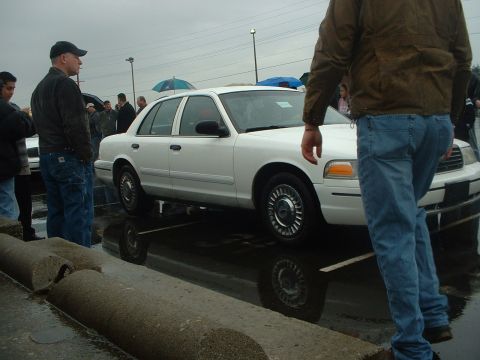 1999 Ford Crown Victoria - White 1999 Ford Crown Victoria seen from the side at an outdoor event with people present.