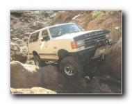 1990 Ford Bronco - This 1990 Ford Bronco is shown tackling a challenging off-road course with steep inclines and large rocks.