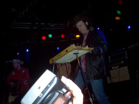 1988 Ford Bronco - Two musicians play instruments on a dimly lit stage, with colorful lights overhead.
