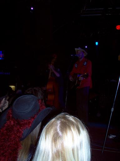 1988 Ford Bronco - A band plays a live set on stage, with a guitarist in a cowboy hat and a bassist visible, to an audience in the foreground.