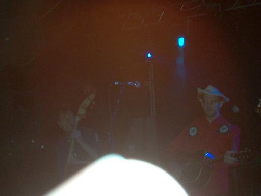 guy in cowboy hat playing guitar on stage, another musician behind him