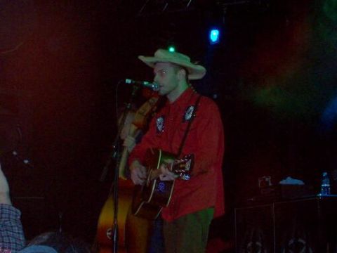 1988 Ford Bronco - Musicians perform live on stage under colored lights, with guitars and microphones visible.