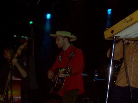1988 Ford Bronco - Musicians perform on stage under colored lights, with instruments and equipment visible.
