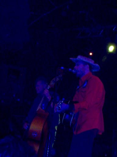 1988 Ford Bronco - Musicians perform on stage with guitars, illuminated by blue stage lighting.
