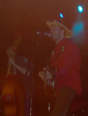 1988 Ford Bronco - A man wearing a cowboy hat sings and plays guitar on stage with another musician.