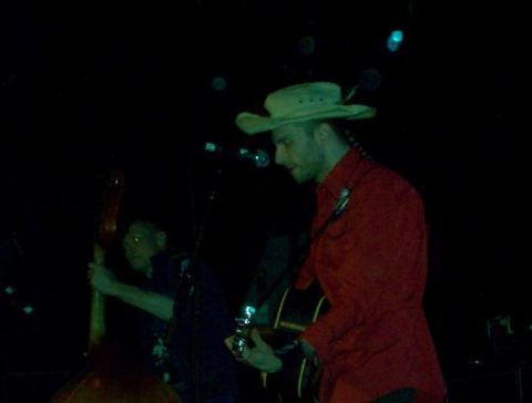 1988 Ford Bronco - Musicians perform live on stage under dim lighting, with one playing guitar and the other an upright bass.