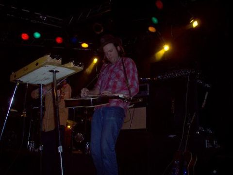 1988 Ford Bronco - Musicians perform on stage under colorful spotlights, with various instruments and equipment visible.