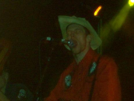1988 Ford Bronco - A performer wearing a cowboy hat and red shirt sings into a microphone under stage lights.