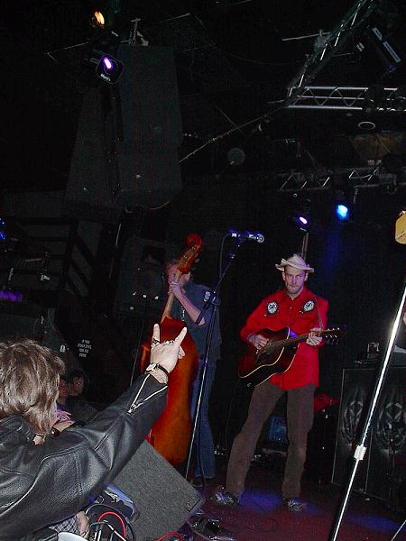 1988 Ford Bronco - A band plays live music on stage, with a guitarist in red and a bassist visible.