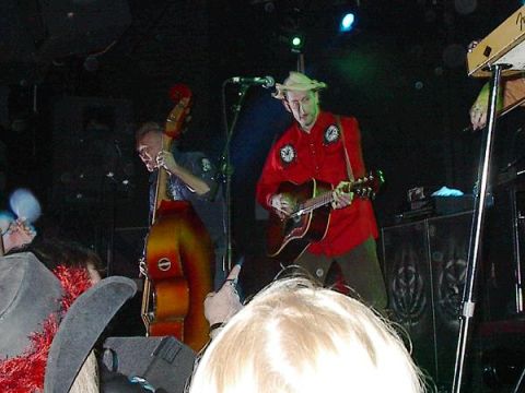 1988 Ford Bronco - A band performs live music on stage, with a guitarist in a red shirt and a bassist with an upright bass.