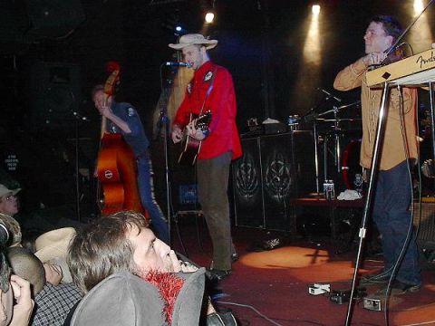 1988 Ford Bronco - A band plays music on stage with a double bass, guitar, and fiddle player.