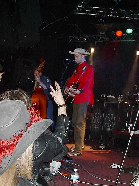 1988 Ford Bronco - A band performs live on stage, with a singer in a red shirt and cowboy hat at the microphone.
