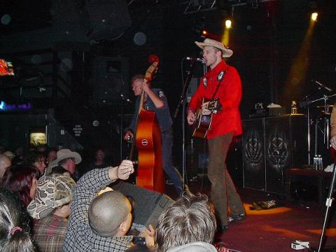 1988 Ford Bronco - A band plays live music on stage, with a guitarist in a red jacket and a bassist with an upright bass.