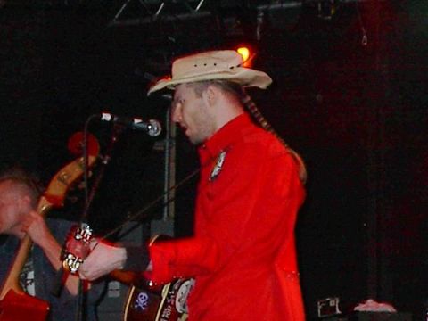 1988 Ford Bronco - Musicians perform live on stage under dark lighting, with microphones and instruments visible.