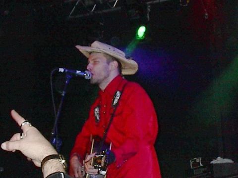 1988 Ford Bronco - A musician wearing a cowboy hat and a red shirt performs on stage with a guitar.