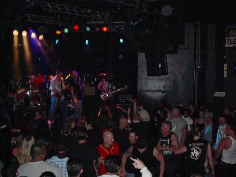1988 Ford Bronco - A band performs live on stage in a dimly lit, crowded music venue.