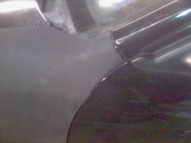 Blurry close-up of dark car fender and hood seam near windshield cowl
