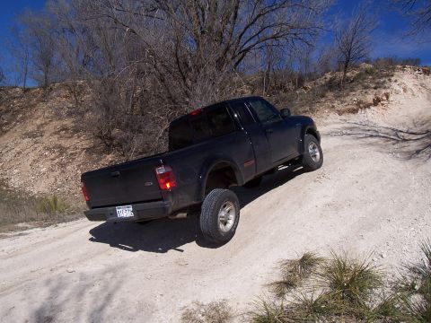 2003 Ford Ranger - A black 2003 Ford Ranger pickup truck navigates an off-road dirt path under a clear blue sky.