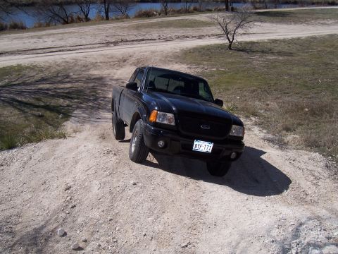2003 Ford Ranger - A black Ford Ranger pickup truck navigates a dirt path with a river in the background.