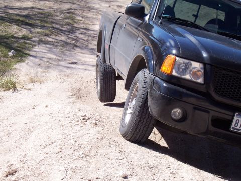 2003 Ford Ranger - A black pickup truck is parked on a dirt road, showing its front right side and lifted suspension.