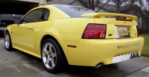 2002 Ford Mustang - Yellow 2002 Ford Mustang GT with a spoiler and GT badge visible from the rear quarter.