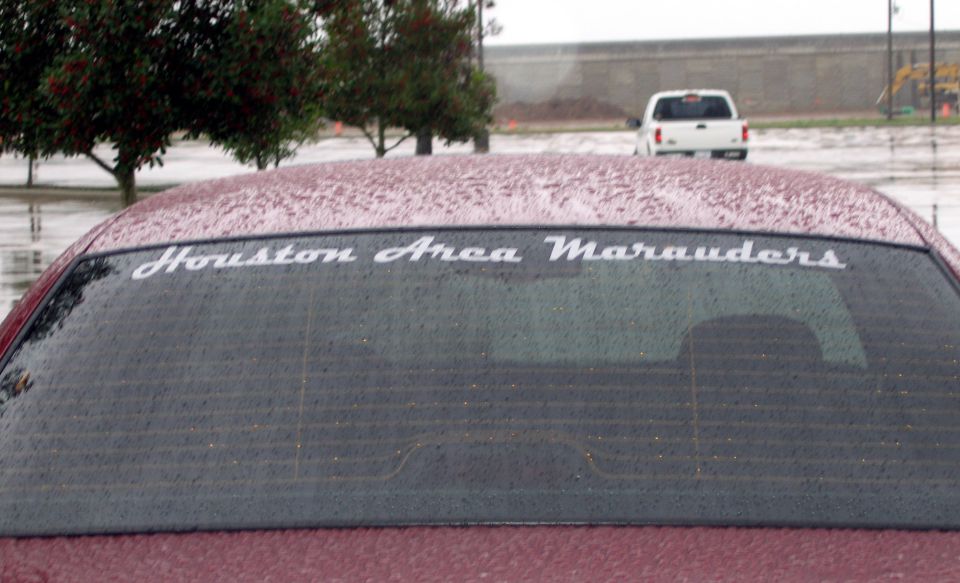 Rear window decal reading Houston Area Marauders on a maroon car in a wet parking lot