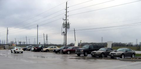 2000 Ford Crown Victoria - A variety of vehicles are parked in an outdoor lot on an overcast day.