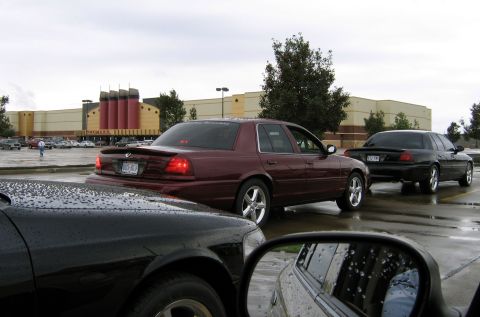 2000 Ford Crown Victoria - A maroon sedan with a spoiler is seen from the rear in a parking lot, with other vehicles present.