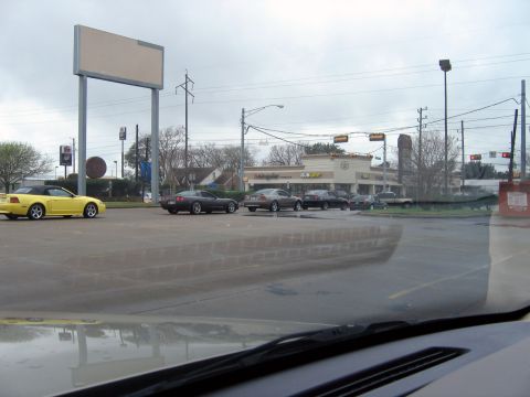 2000 Ford Crown Victoria - A yellow convertible is parked in a lot with other vehicles, under an overcast sky.